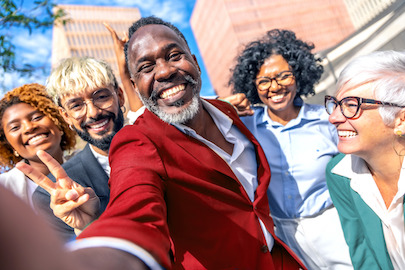 Ljudi različite dobi, rase i spola koji se široko smiju ispred zgrade